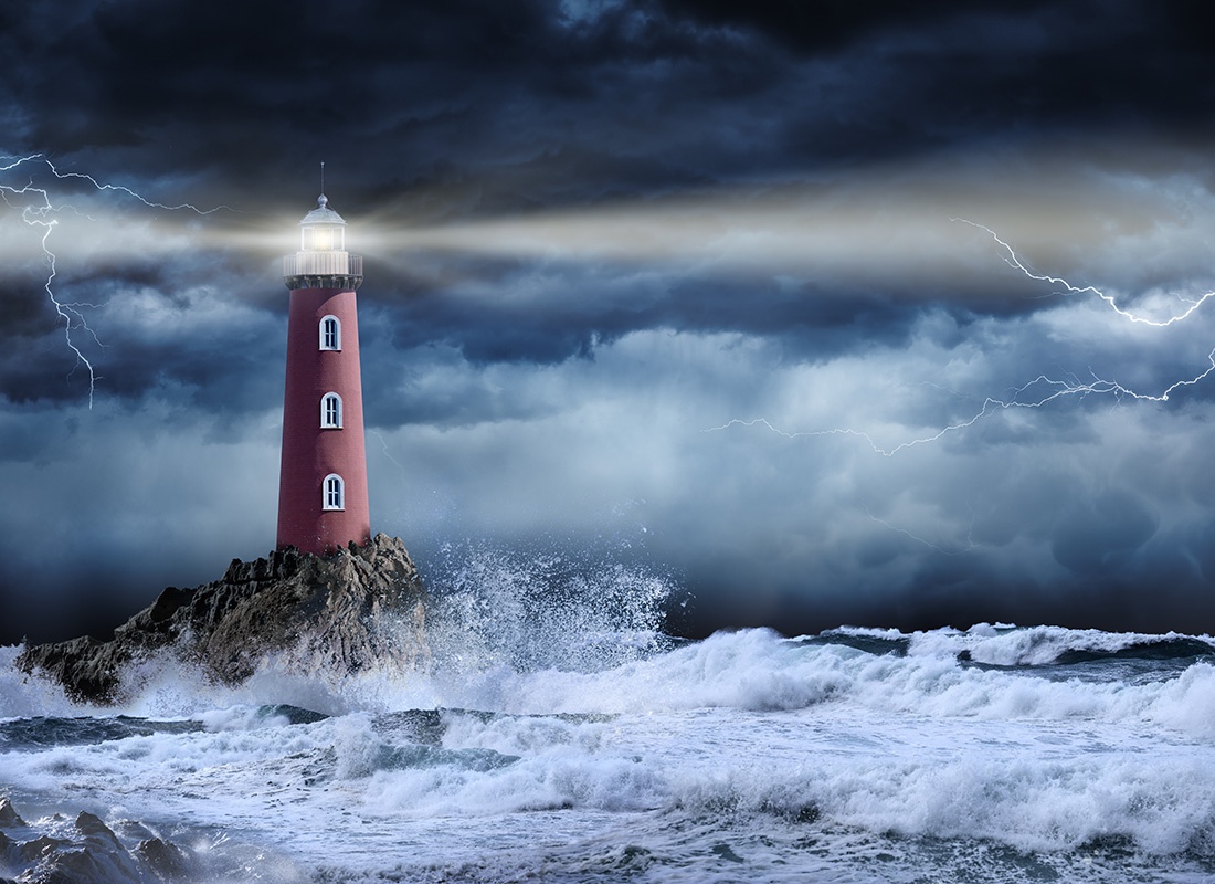 About Our Agency - Art of a Lighthouse on a Rock Shining Beams of Light Out into the Ocean During a Bad Storm