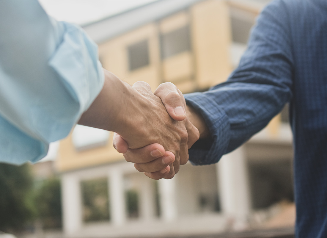 Preferred Vendors - Closeup View of Two Businessmen Shaking Hands While Standing Outside with a Commercial Building Visible in the Background